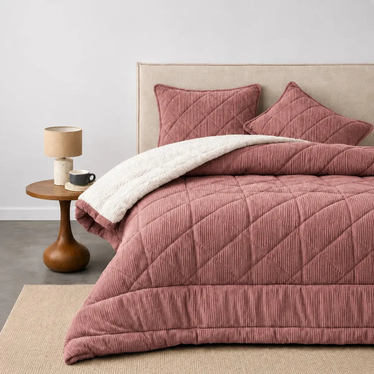 Plumón rosa palo con sherpa blanco sobre una cama, en un dormitorio luminoso