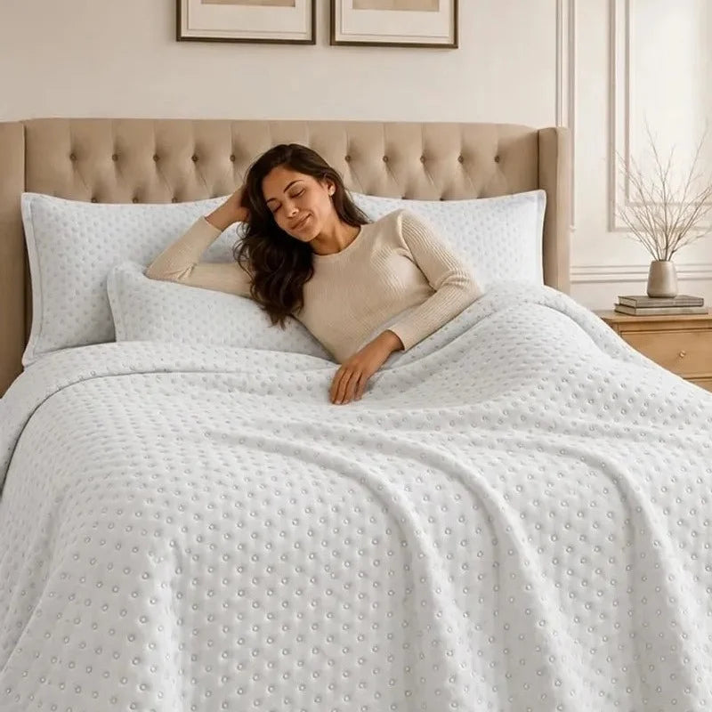 Mujer recostada sobre un quilt blanco en una cama con cabecera acolchada